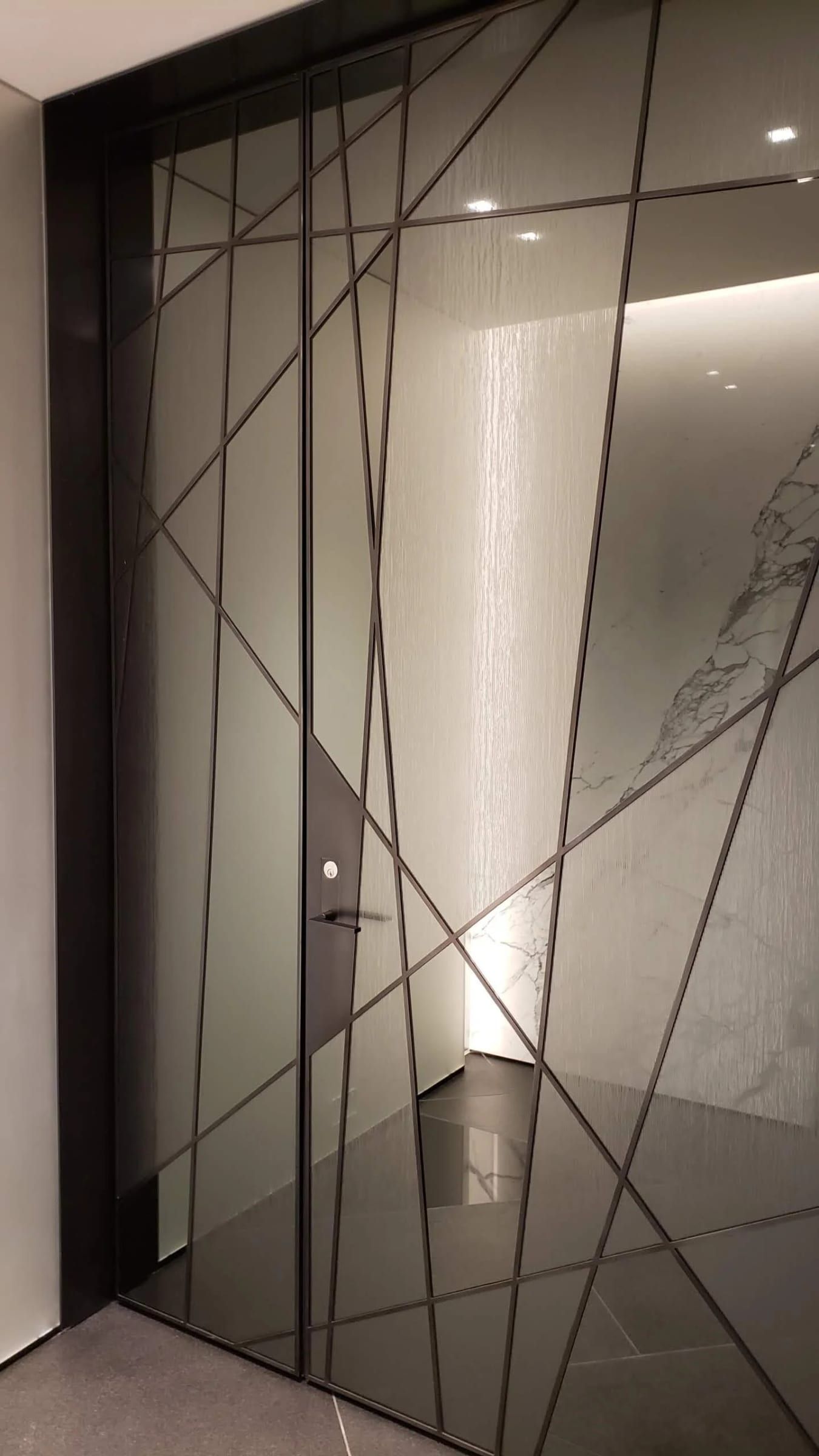 Angled blackened stainless mullions across tinted glass