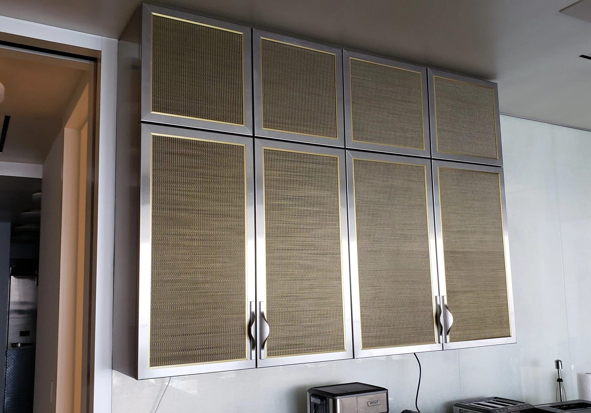 Upper cabinets with brass frames and woven metal mesh fronts
