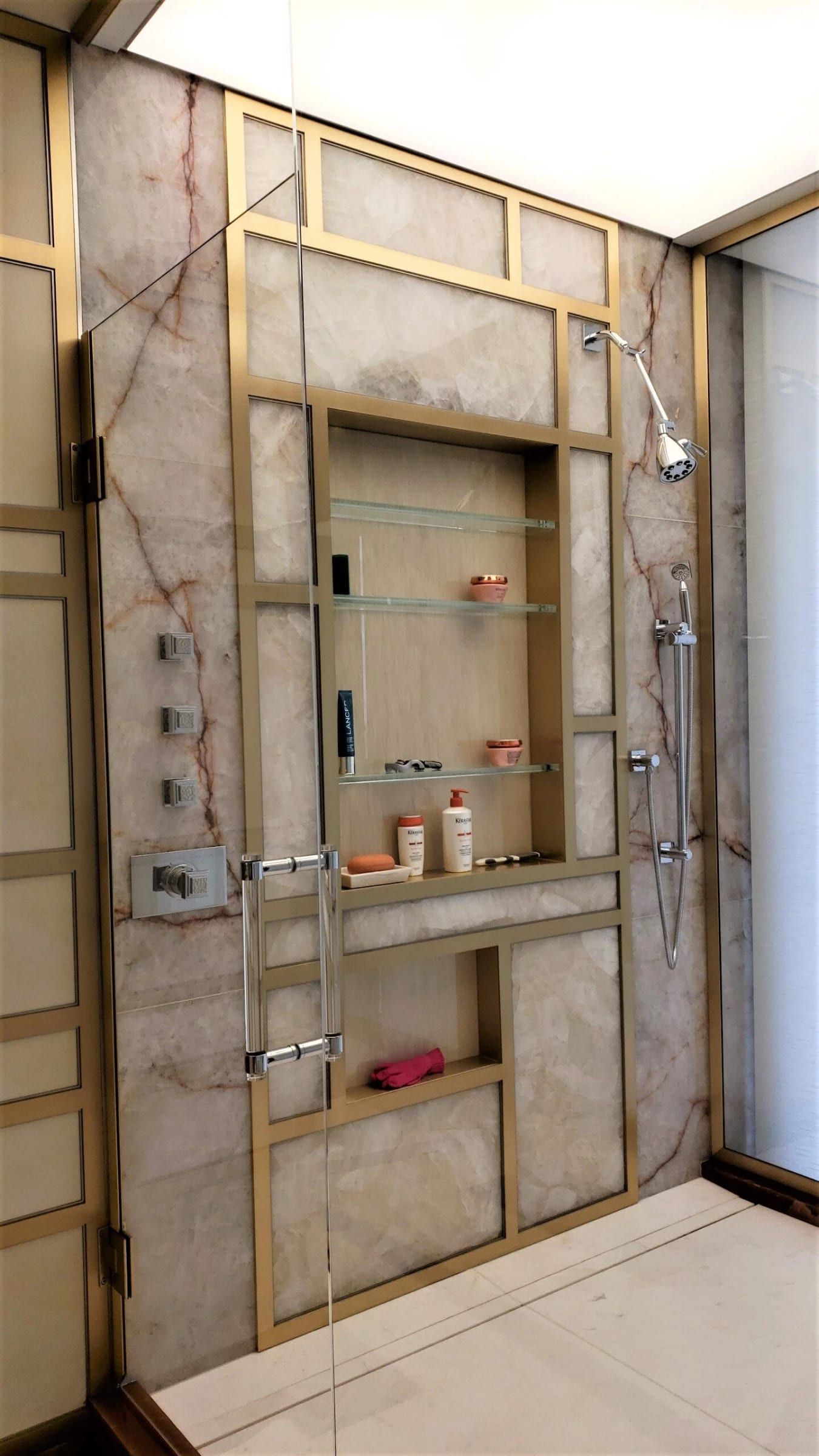Shower wall with a brass grid and recessed niches