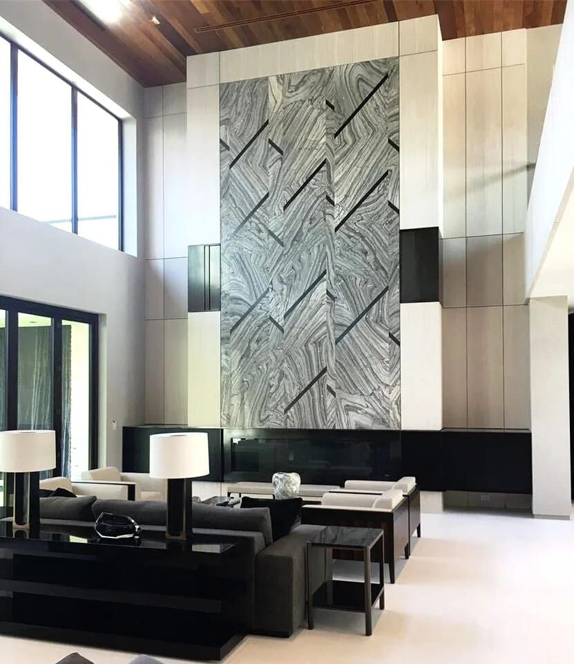 Double-height living room with a stone feature wall framed in blackened steel