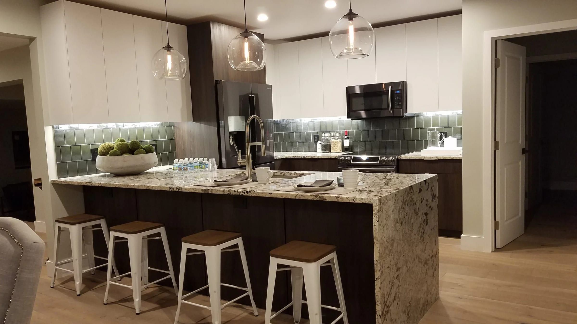 Remodeled kitchen with a waterfall granite island and four stools
