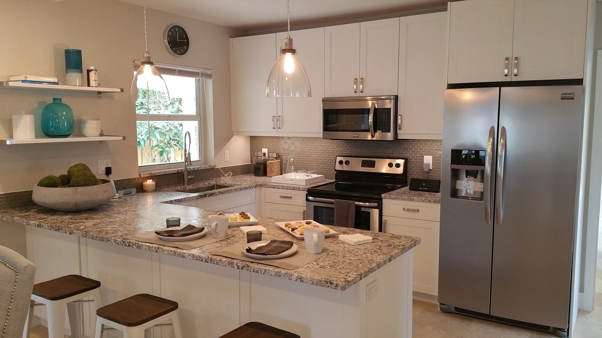 White kitchen with a granite peninsula and stainless appliances